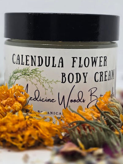 Jar of calendula flower body cream with dried flowers on a white background