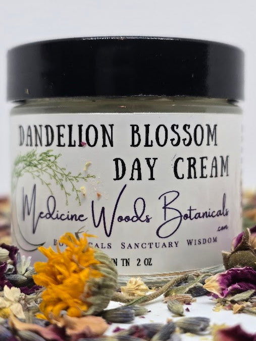 Jar of Dandelion Blossom Day Cream from Medicine Woods Botanicals surrounded by dried flowers and herbs.