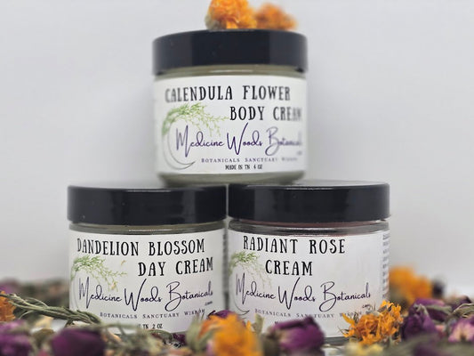 Three jars of Medicine Woods Botanicals cream with dried flowers on a white background